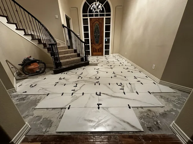 Large-format floor tile being laid with leveling clips.
