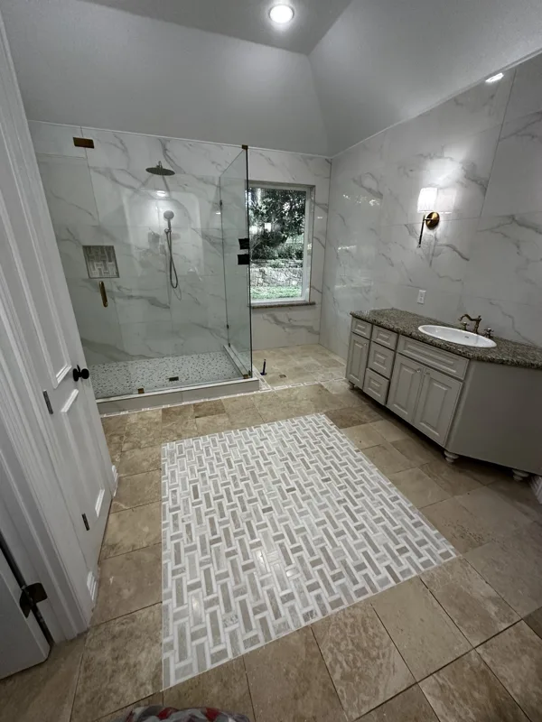 Large-format wall tile and a glass shower enclosure.