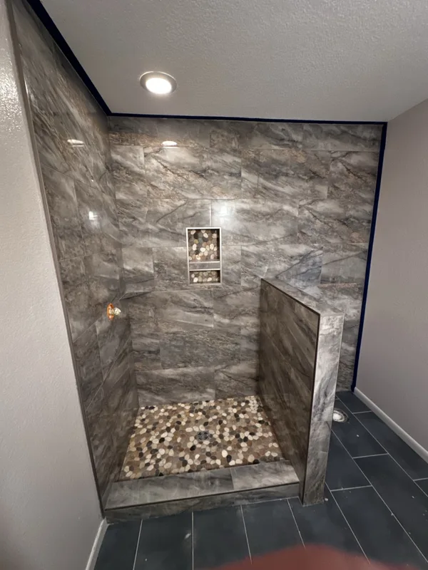 Rich wall texture paired with a pebble-style shower floor.