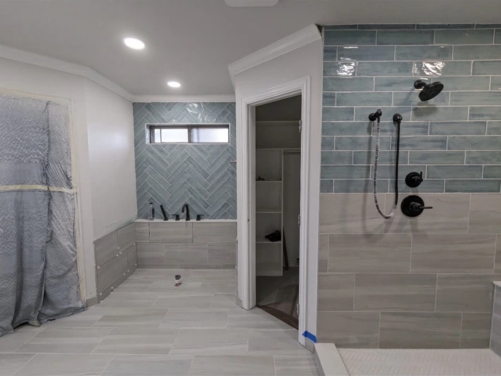 Bathroom with blue tile feature walls, a herringbone tub surround, and a walk-in shower